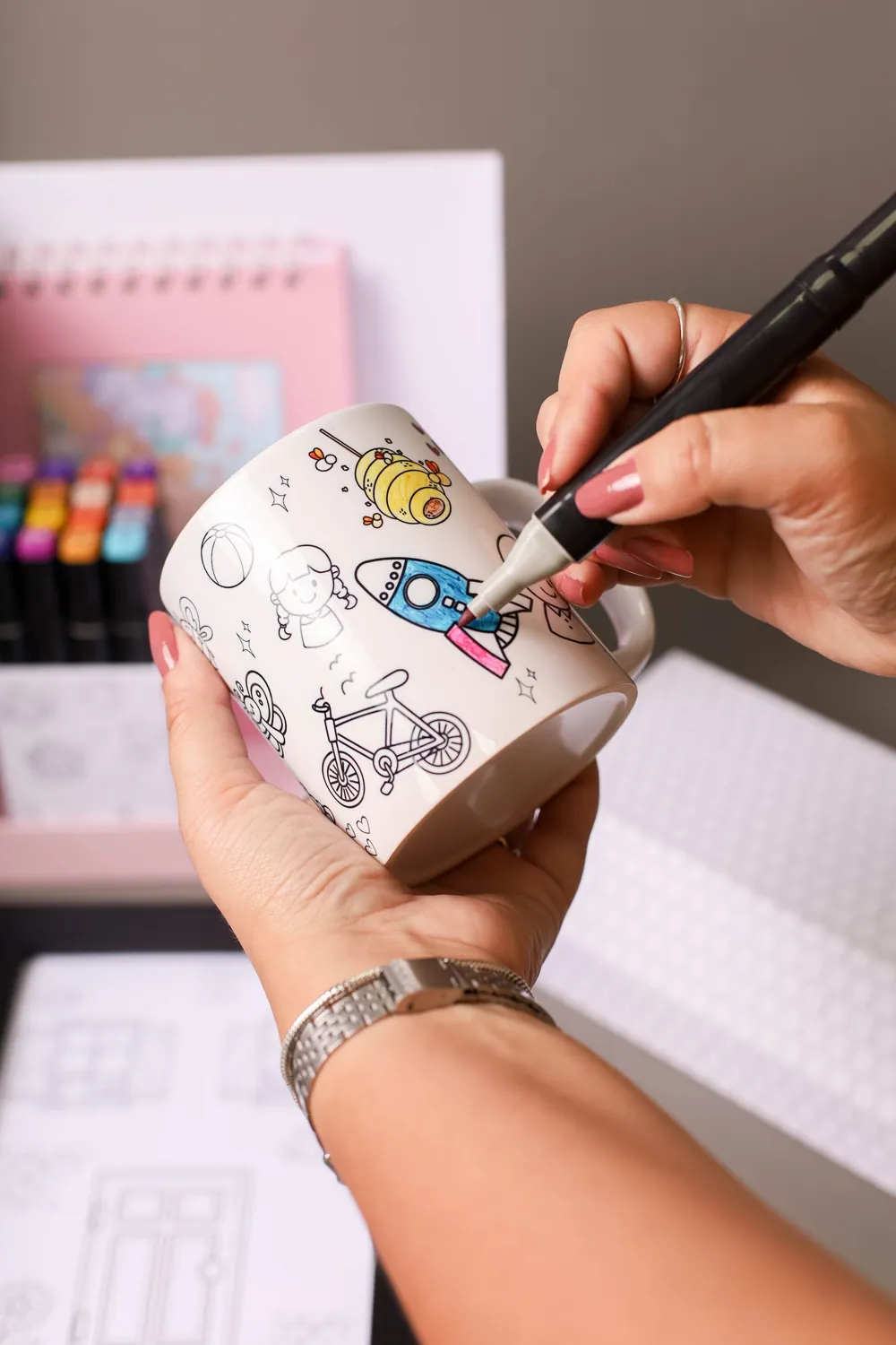 Mãos desenhando sobre a arte da Casinha dos Artistas.